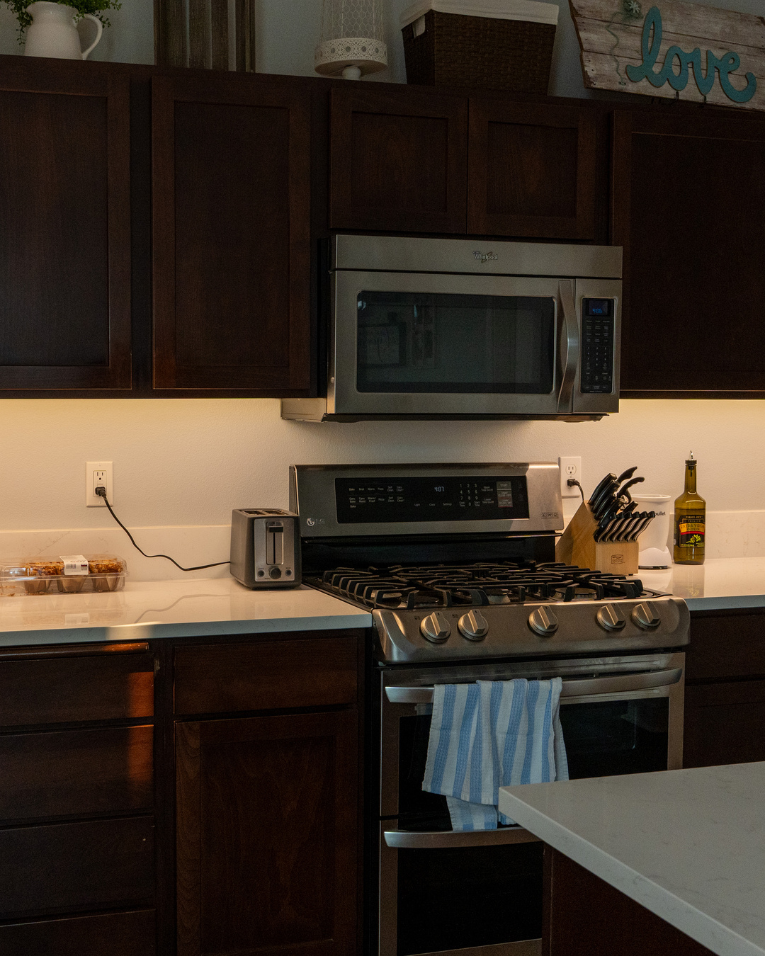 Warm under-cabinet lighting installed around a kitchen range